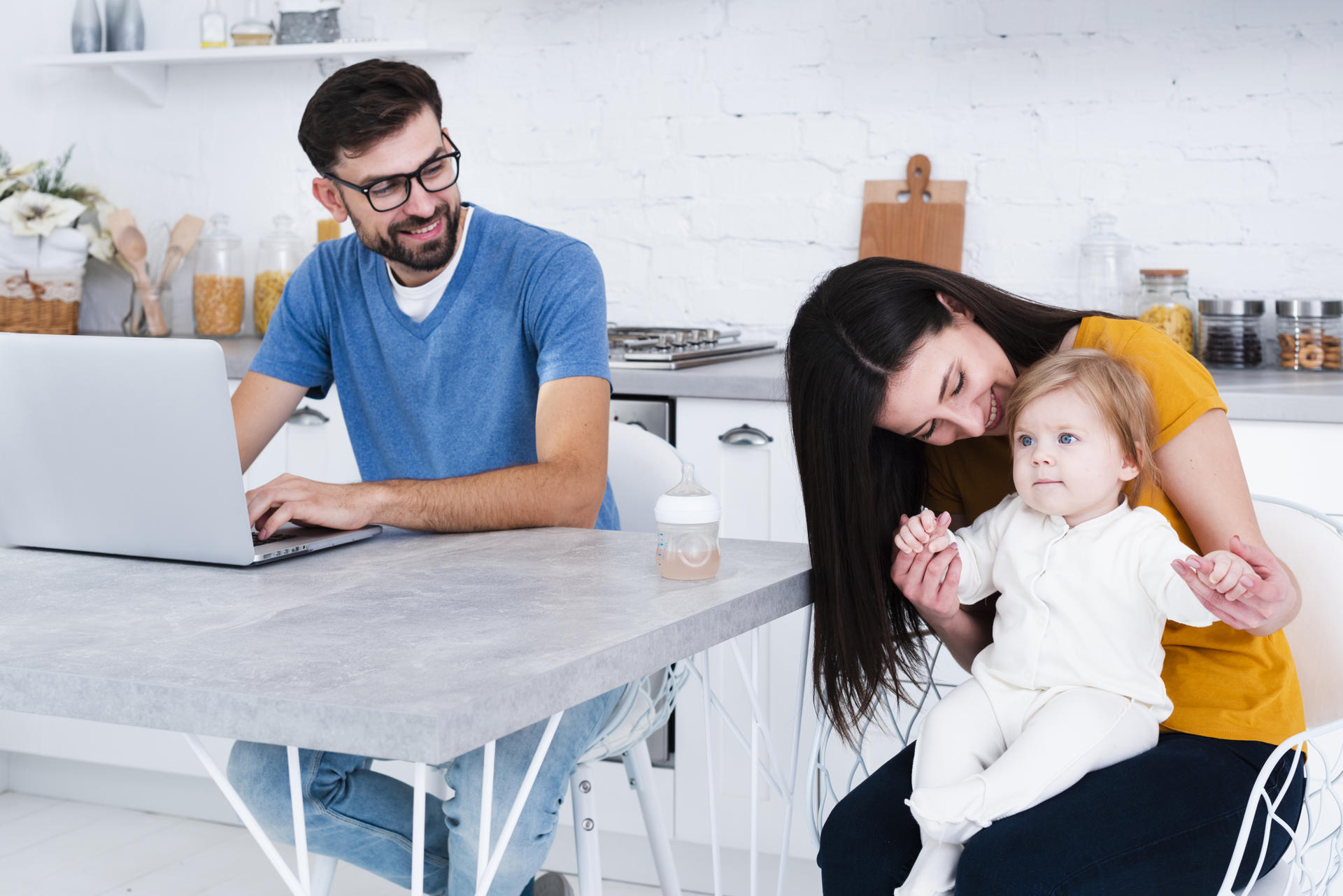 woman-holding-baby-with-man-working